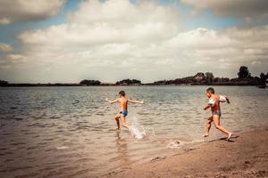 crianças pequenas se divertindo enquanto correm no mar em dia de verão. foto