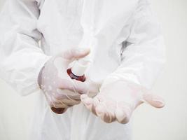 retrato de médico ou cientista em uniforme de conjunto de ppe segurando garrafa de plástico com produto para cuidados com a pele. fundo branco isolado conceito covid-19 foto