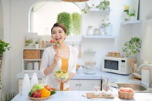 fechar o retrato de linda garota comendo salada na cozinha foto