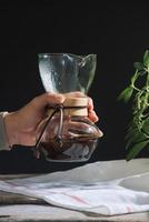 conceito de café de fermentação por gotejamento. mesa de madeira com bolo de chocolate e café em fundo preto. foto