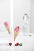 cone de waffle cheio de sorvete de framboesa fresca em copo de vidro com framboesa fresca sentada na mesa foto