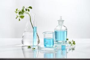 equipamento de vidro de laboratório com ingredientes naturais em fundo branco foto