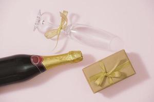 Flat lay elegante conjunto champanhe, presente, bolas de natal e decoração de férias douradas. postura plana, vista superior. foto