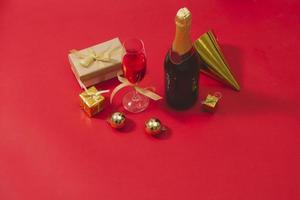 champanhe e enfeites de natal no fundo da mesa vermelha foto