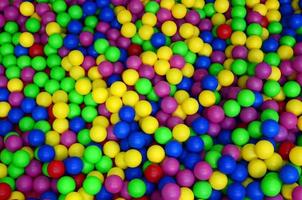 muitas bolas de plástico coloridas em uma piscina infantil em um playground. padrão de close-up foto