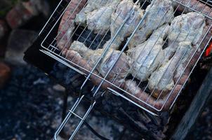 shish kebabs de asas de frango são fritos no campo. um churrasco clássico ao ar livre. o processo de fritar carne no carvão foto