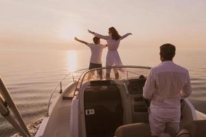 um casal sênior em roupas casuais com seu filho desfruta enquanto andava de barco no mar ao pôr do sol. o conceito de uma família feliz. foco seletivo foto