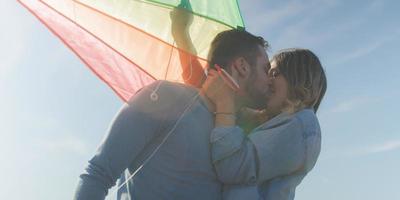 casal feliz se divertindo com pipa na praia foto