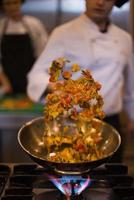 chef lançando legumes no wok foto