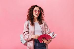 linda adolescente de casaco rosa segurando notebooks em fundo isolado foto