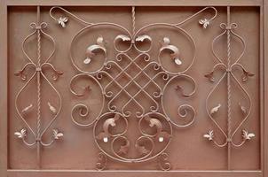 a textura do portão de metal bronze com um belo padrão floral de metal forjado foto