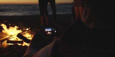 casal tirando fotos ao lado da fogueira na praia