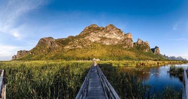 ponte de madeira no lago de lótus sob céu nublado no parque nacional de khao sam roi yod, tailândia. foto