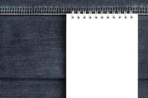 caderno branco com páginas limpas sobre fundo de jeans azul escuro. imagem com espaço de cópia foto