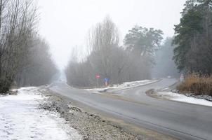 encruzilhada em uma estrada de asfalto suburbano no inverno durante uma nevasca foto