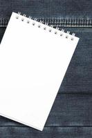 caderno branco com páginas limpas sobre fundo de jeans azul escuro. imagem com espaço de cópia foto