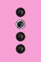 algumas lentes de câmera com uma abertura fechada estão no fundo de textura de papel de cor rosa pastel de moda em conceito mínimo. padrão abstrato na moda foto