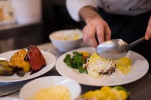 mãos de chef servindo risoto de legumes foto