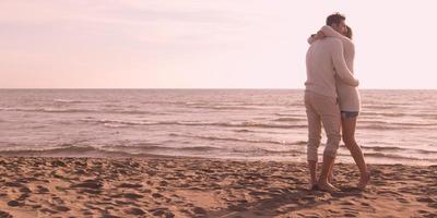 amando o jovem casal em uma praia no outono em dia ensolarado foto