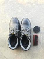 sapatos de segurança pretos ao lado de uma escova de sapato e graxa de sapato foto