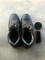 sapatos de segurança pretos ao lado de uma escova de sapato e graxa de sapato foto