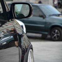 vista diagonal de um carro preto brilhante com rodas brancas, que fica em um quadrado de azulejos cinza foto