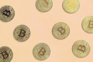 muitos bitcoins dourados estão em um cobertor feito de tecido de lã laranja claro macio e fofo. visualização física da moeda criptográfica virtual foto