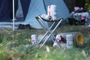 sumy, ucrânia - 01 de agosto de 2021 algumas latas de cerveja de álcool budweiser lager na cadeira de pescador ao ar livre. budweiser é uma marca da anheuser-busch inbev foto