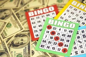 muitos tabuleiros de bingo ou cartas de baralho para ganhar fichas e grande quantidade de notas de dólar. clássico americano ou canadense cinco a cinco cartões de bingo em dinheiro foto