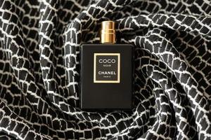 ternopil, ucrânia - 2 de setembro de 2022 coco noir chanel paris mundialmente famoso frasco de perfume francês na velha manta com padrão monocromático foto