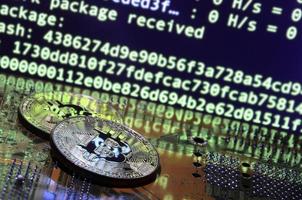 dois bitcoins estão em uma superfície de placa de vídeo com fundo de exibição de tela de mineração de criptomoeda usando o gpus foto
