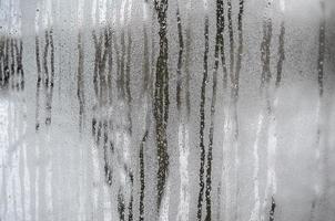 a textura de um vidro embaçado com muitas gotas e fluxos de condensação. imagem de fundo foto