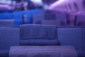 assentos de avião de passageiros vazios de cor roxa na cabine foto