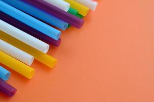 muitos canudos coloridos para bebidas estão em uma superfície de fundo laranja brilhante foto