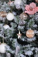 decorar a árvore de natal de perto. lâmpada de decoração, pinheiro verde nevado, brinquedos de Natal rosa e luzes. use para fundo de celebração de natal e ano novo foto