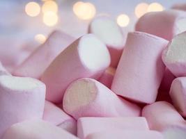 uma foto aproximada de um saboroso marshmallow rosa-branco com luzes em um fundo