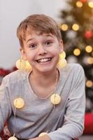 retrato de um menino de natal. linda criança sorridente se divertindo com bolas de natal. foto