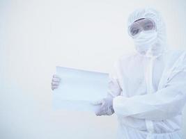 jovem médico ou cientista em uniforme de suíte de EPI segurando papel em branco para texto com as duas mãos enquanto olha para a frente. coronavírus ou covid-19 conceito isolado fundo branco foto