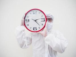 retrato de médico ou cientista em uniforme de suíte de ppe segurando o despertador vermelho e olhando para a câmera em vários gestos. fundo branco isolado conceito covid-19 foto