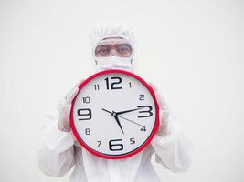 retrato de médico ou cientista em uniforme de suíte de ppe segurando o despertador vermelho e olhando para a câmera em vários gestos. fundo branco isolado conceito covid-19 foto