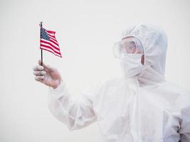 retrato de médico ou cientista em uniforme de conjunto de ppe segurando a bandeira nacional dos estados unidos da américa. fundo branco isolado conceito covid-19 foto