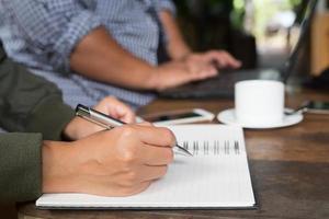 freelancer de mulher trabalhando à mão escrevendo o diário no bloco de notas do notebook pequeno na cafeteria usando com área de espaço de cópia. foto