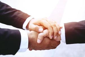 closeup de um investidor de aperto de mão empresário entre dois colegas ok, ter sucesso nos negócios de mãos dadas. foto
