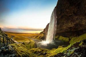 seljalandsfoss, uma cachoeira com uma pequena caverna atrás dela na região sul da islândia, faz parte do rio seljalands que tem sua origem na geleira do vulcão eyjafjallajokull foto