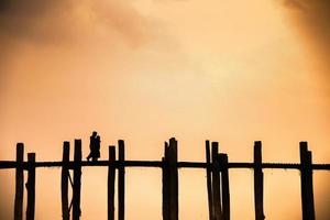 silhueta de um casal andando na ponte u bein com céu crepúsculo por do sol no fundo, mandalay, mianmar foto