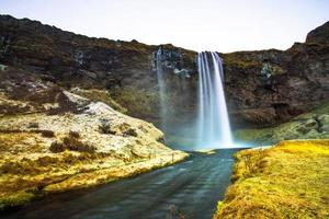 seljalandsfoss, uma cachoeira com uma pequena caverna atrás dela na região sul da islândia, faz parte do rio seljalands que tem sua origem na geleira do vulcão eyjafjallajokull foto