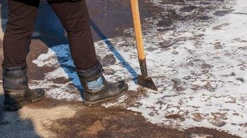 uma trabalhadora limpa o gelo e remove a neve das lajes de pavimentação usando um quebra-gelo. foto