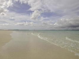 lindo dia ensolarado em uma praia calma e intocada com céu cinza na indonésia foto