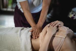 massagem abdominal e spa tratamento relaxante do estilo tradicional de massagem tailandesa da síndrome do escritório. asain massagista feminina fazendo massagem tratar abdômen relaxar e estresse para mulher de escritório cansada do trabalho. foto