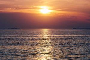 mar calmo com céu pôr do sol, bela vista panorâmica, incrível sol nascente dramático refletido na água foto